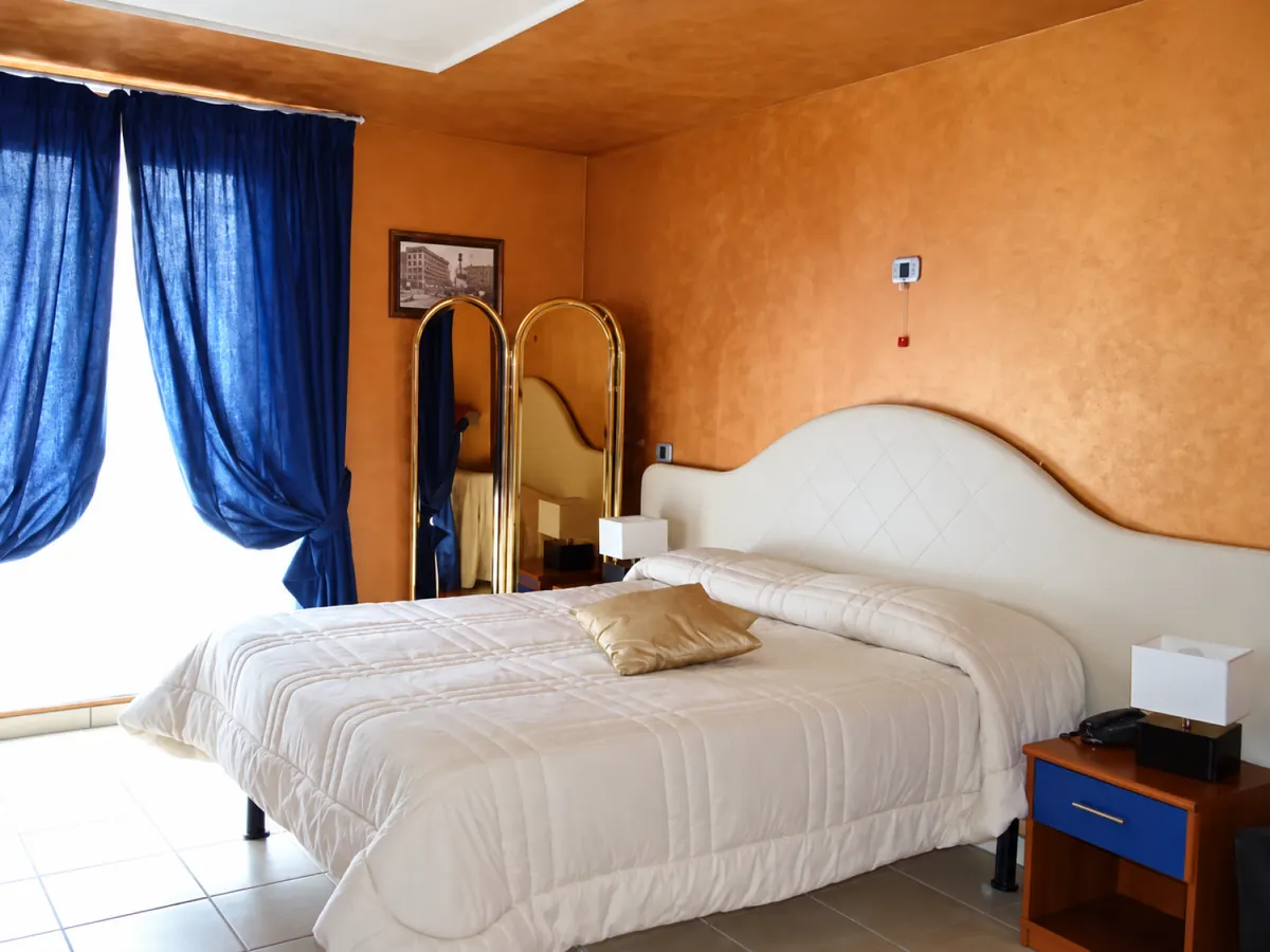 Camera doppia con letto bianco e tende blu